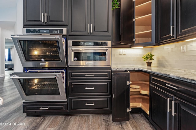 kitchen featuring dark hardwood / wood-style floors, light stone counters, double oven, and tasteful backsplash