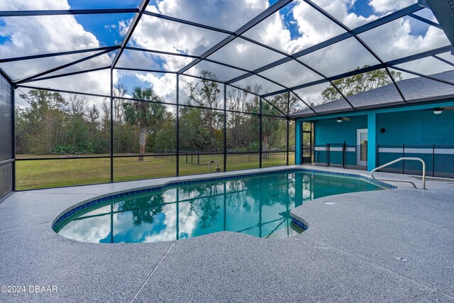 view of pool featuring a patio, glass enclosure, and ceiling fan