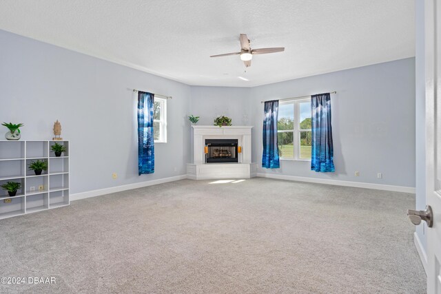 unfurnished living room featuring ceiling fan, carpet, and a textured ceiling