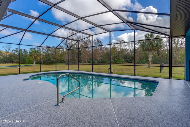 view of pool with a lawn, glass enclosure, and a patio