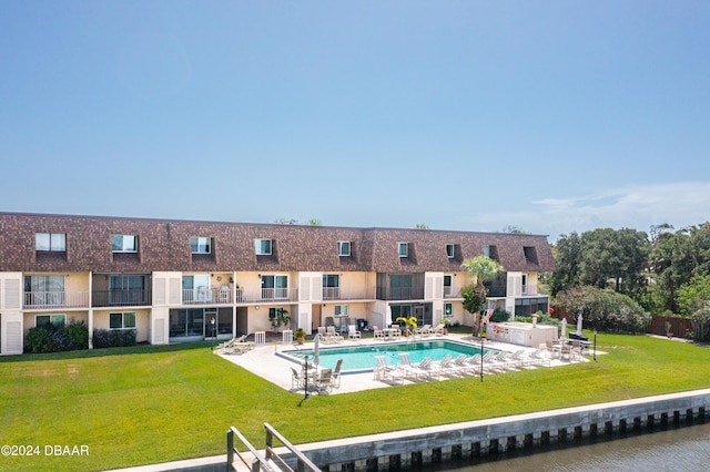 view of pool with a lawn, a patio, and a water view