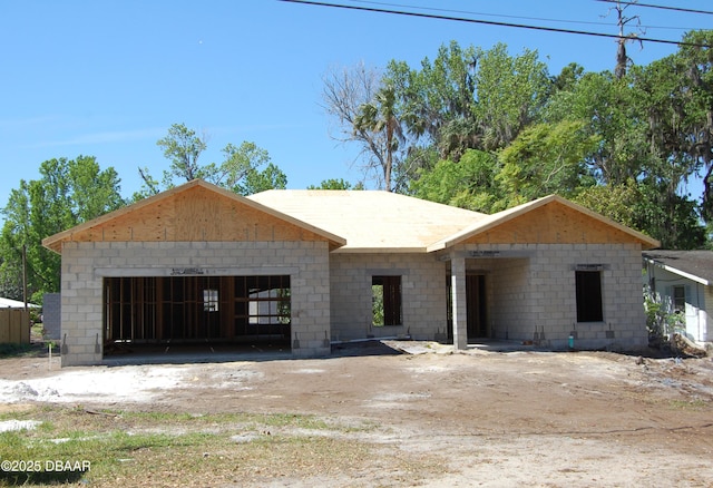 unfinished property with concrete block siding and a garage