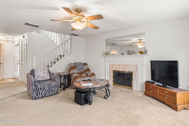 living room featuring stairway, carpet, visible vents, a fireplace, and a textured ceiling