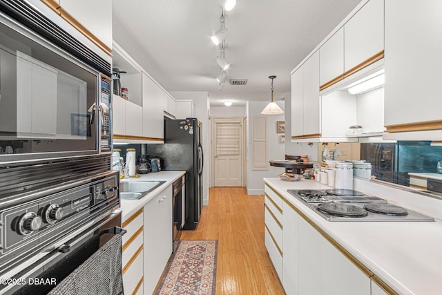 kitchen with visible vents, light wood-type flooring, light countertops, white cabinets, and black appliances