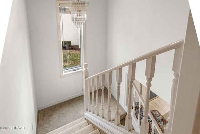 staircase with baseboards, carpet floors, and a chandelier