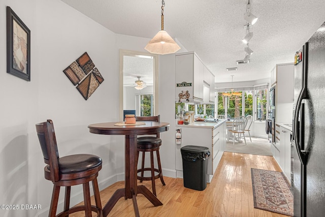 dining space with light wood-style flooring, baseboards, and a textured ceiling