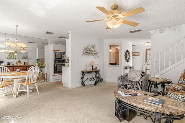 living area featuring visible vents, light colored carpet, a textured ceiling, and stairs