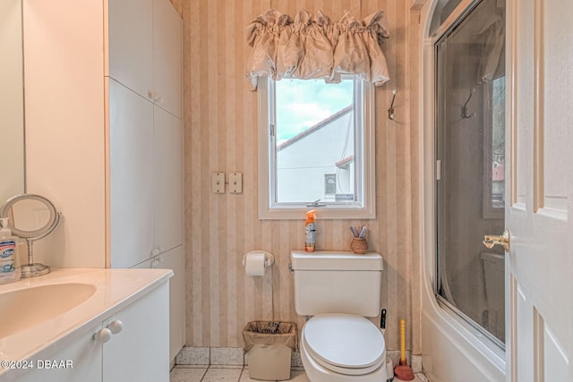 bathroom with wallpapered walls, toilet, shower / bath combination with glass door, tile patterned floors, and vanity