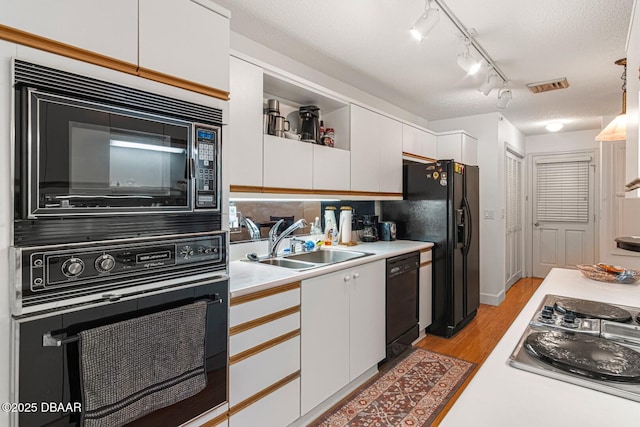 kitchen with visible vents, black appliances, light countertops, white cabinetry, and a sink