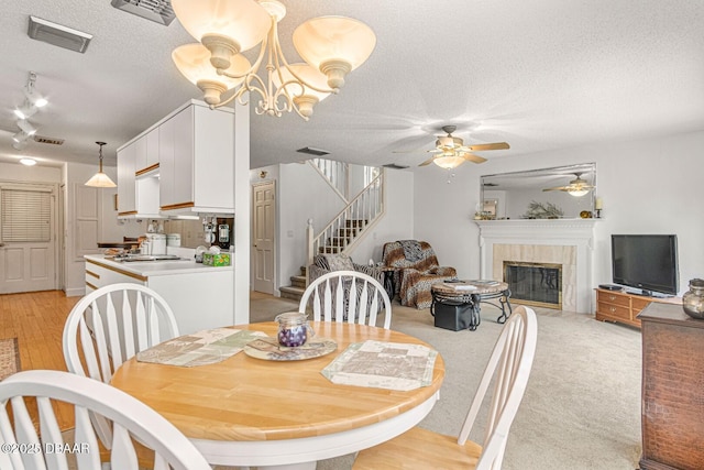 dining area with visible vents, a textured ceiling, a fireplace, and stairway