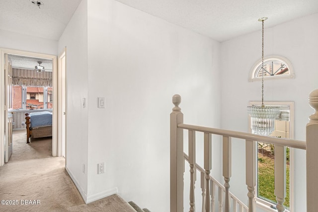 corridor with baseboards, an upstairs landing, plenty of natural light, and carpet flooring