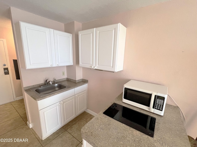 kitchen featuring white cabinets, light tile patterned flooring, white microwave, and a sink