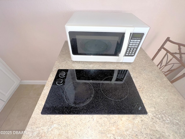 room details with baseboards, black electric stovetop, and white microwave