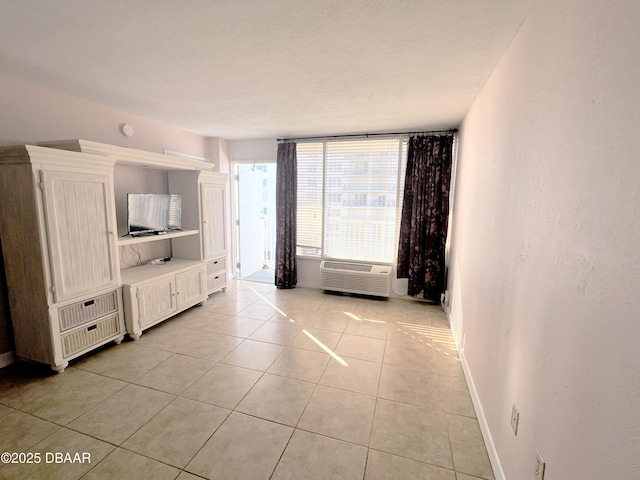 unfurnished living room featuring light tile patterned floors, heating unit, baseboards, and a wall unit AC