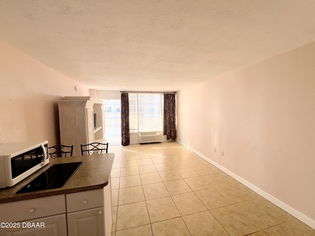 kitchen featuring dark countertops, a textured ceiling, light tile patterned floors, baseboards, and white microwave