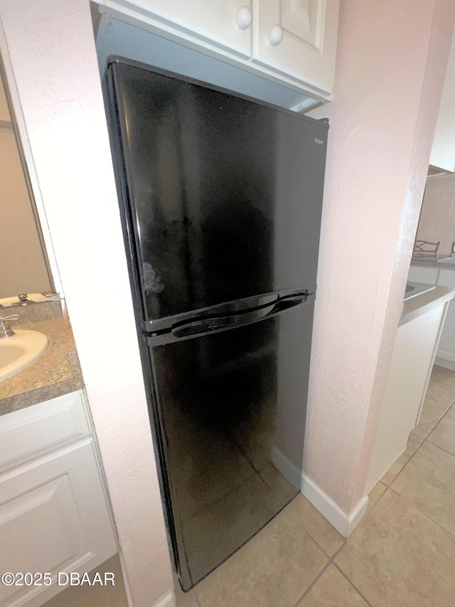 details with baseboards, freestanding refrigerator, and a sink