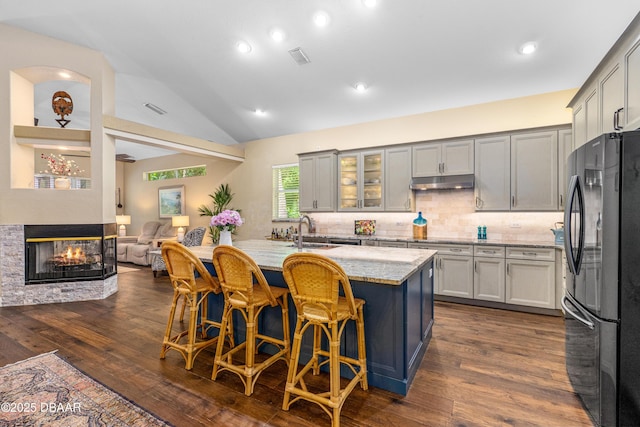 1324 Munster Cir, Ormond Beach, FL 32174 - kitchen featuring freestanding refrigerator, under cabinet range hood, dark wood finished floors, light stone countertops, and vaulted ceiling