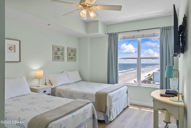 bedroom featuring light wood-style flooring, multiple windows, baseboards, and ceiling fan