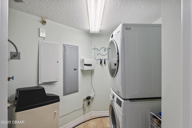laundry area with stacked washer / drying machine, a textured ceiling, baseboards, electric panel, and light tile patterned flooring
