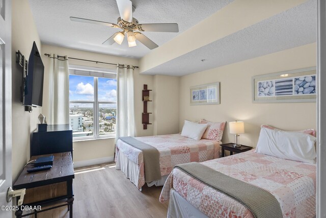 bedroom with wood finished floors, baseboards, a textured ceiling, and ceiling fan