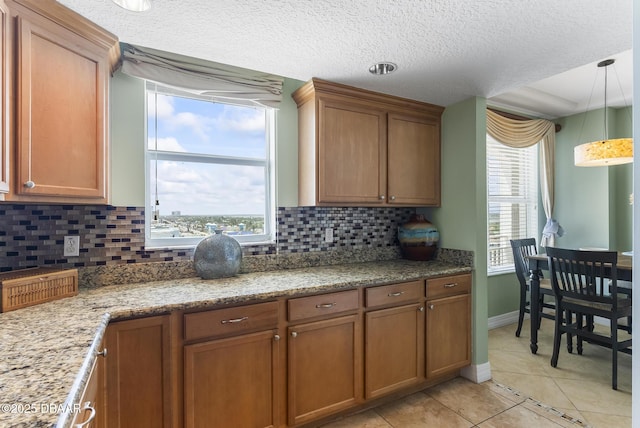 kitchen with brown cabinets, decorative backsplash, light tile patterned floors, and a textured ceiling