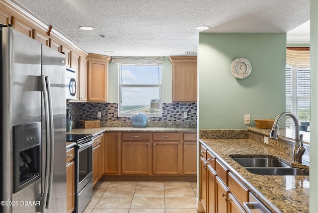 kitchen with stainless steel appliances, a sink, a textured ceiling, decorative backsplash, and stone counters
