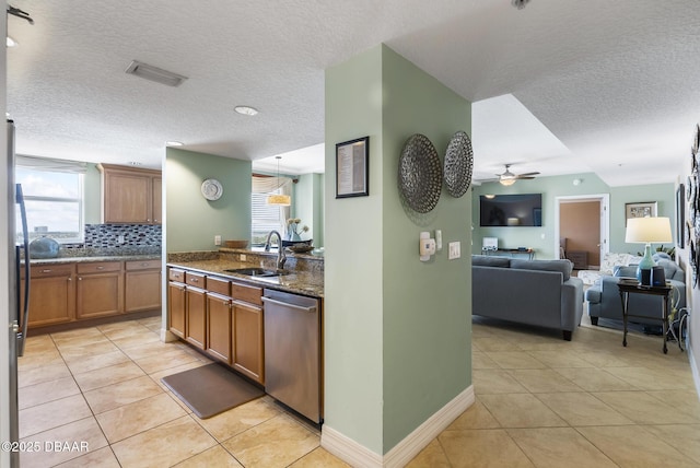 kitchen featuring dishwasher, a sink, light tile patterned flooring, a textured ceiling, and healthy amount of natural light