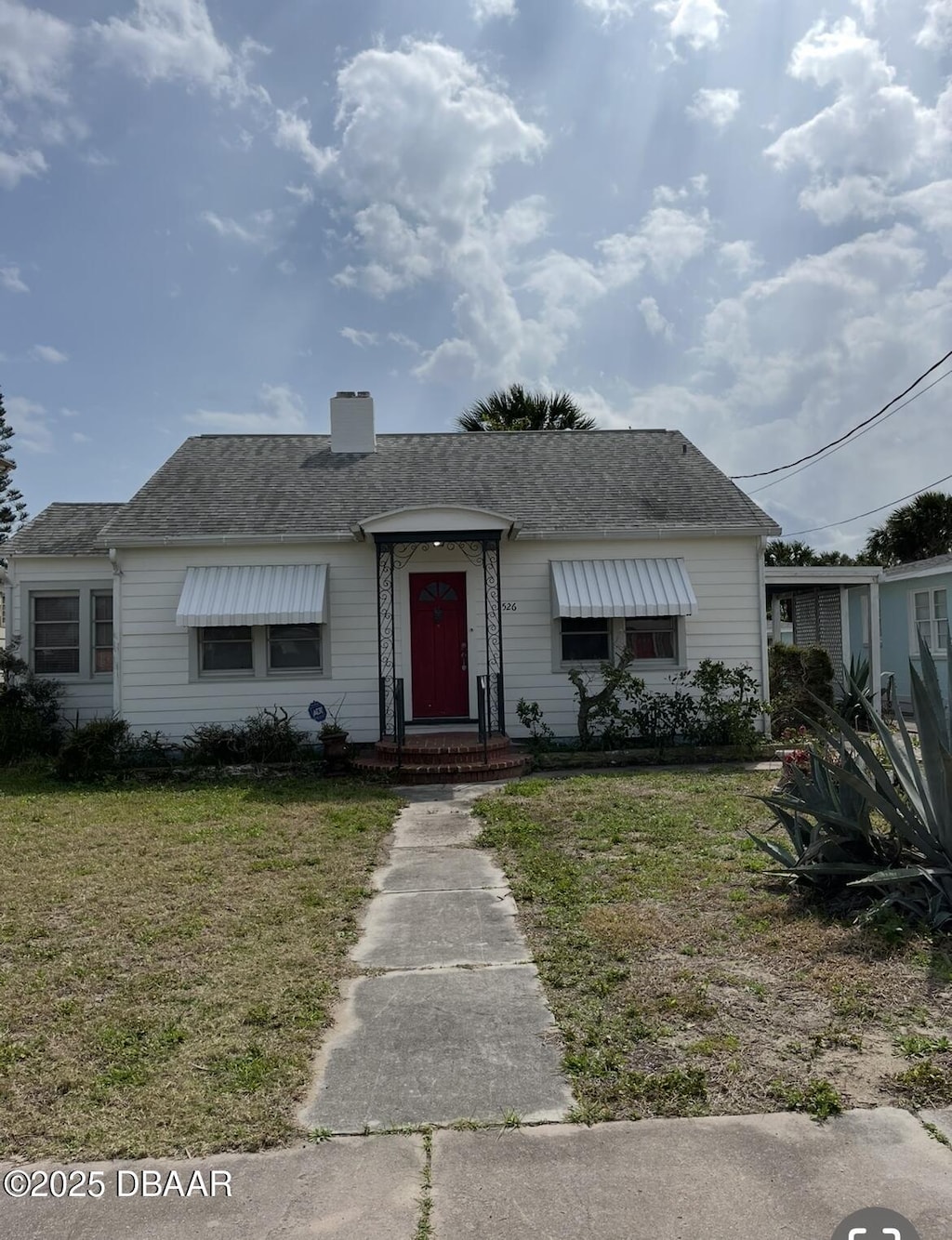 view of front of house featuring a front yard, roof with shingles, and a chimney