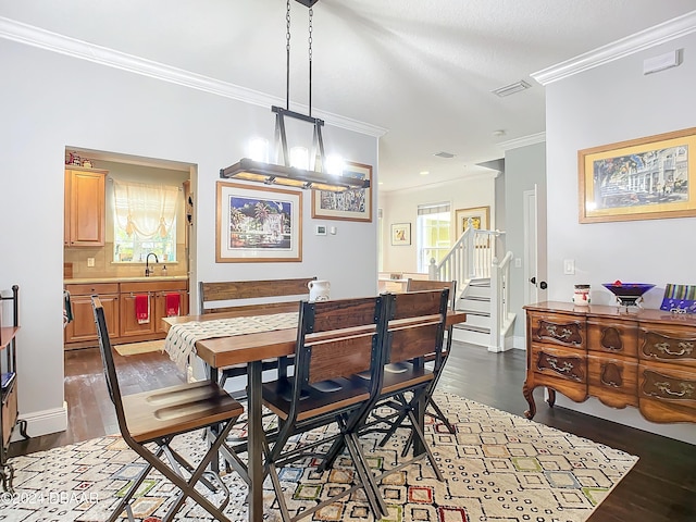 dining space with dark hardwood / wood-style floors, crown molding, and sink