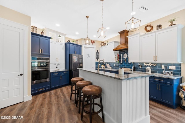 4 Oakview Ct, Palm Coast, FL 32137 - kitchen featuring blue cabinetry, stainless steel appliances, an island with sink, dark wood finished floors, and decorative backsplash