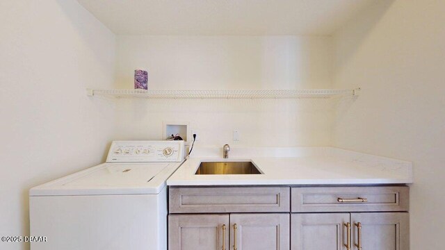 clothes washing area featuring cabinet space, washer / clothes dryer, and a sink