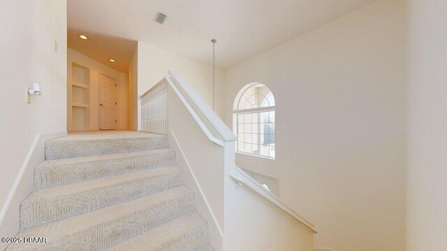 staircase featuring built in features, recessed lighting, baseboards, and visible vents