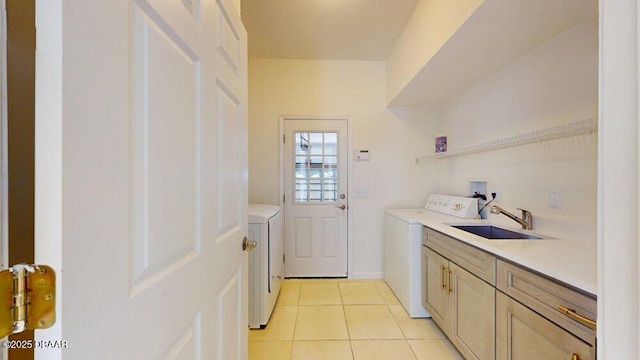 laundry room with a sink, cabinet space, light tile patterned flooring, baseboards, and washing machine and clothes dryer