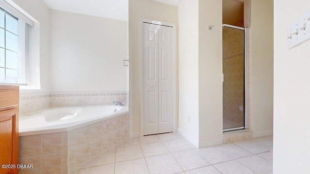 bathroom featuring tile patterned flooring, a shower stall, a garden tub, and a closet