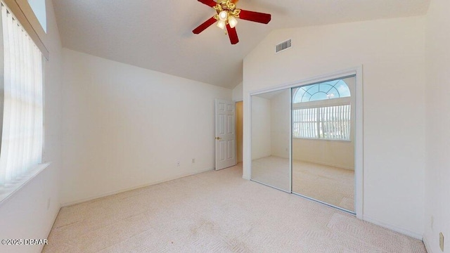 unfurnished bedroom with visible vents, high vaulted ceiling, a closet, carpet floors, and ceiling fan