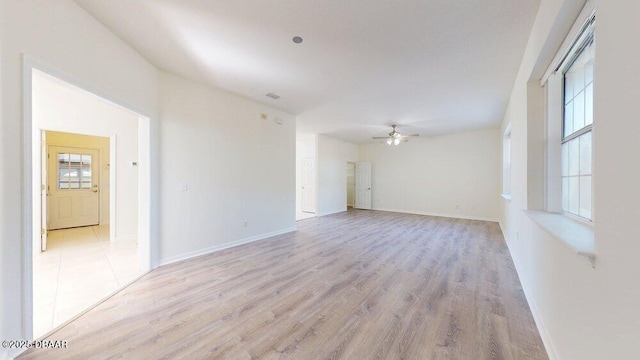 empty room with plenty of natural light, light wood-style floors, and a ceiling fan