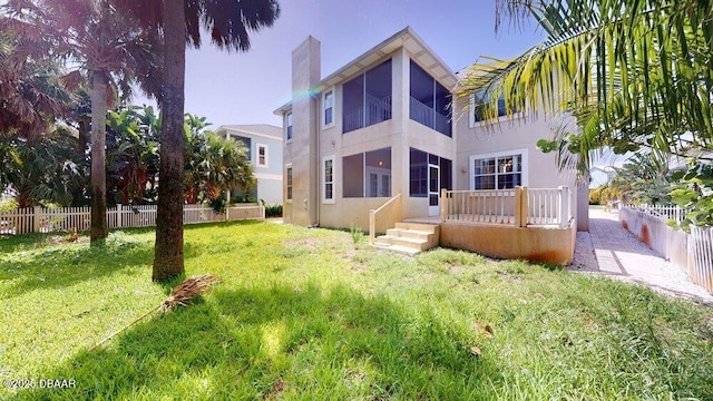 back of property featuring stucco siding, a lawn, a chimney, and fence