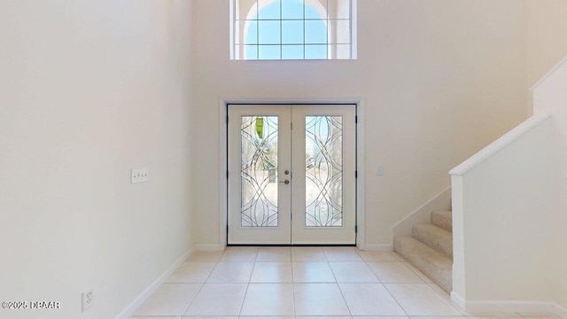 tiled foyer featuring a high ceiling, stairway, french doors, and baseboards