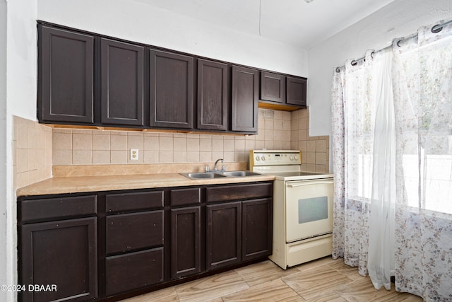 kitchen with dark brown cabinets, decorative backsplash, sink, and white electric range oven