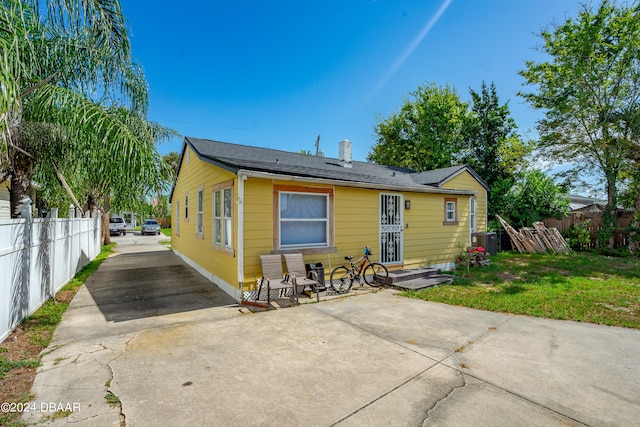 view of front of home with a patio, central AC unit, and a front yard