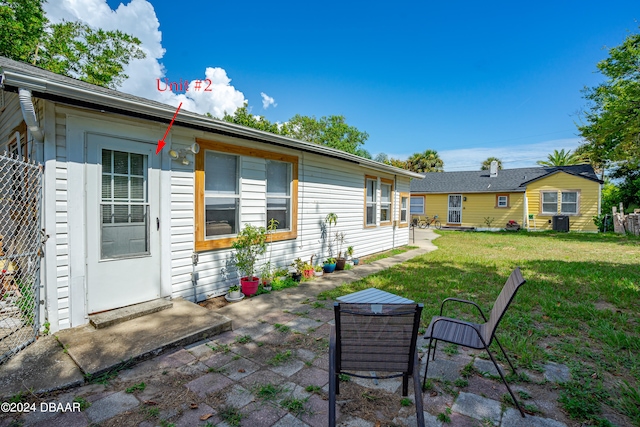 back of house with central AC unit, a yard, and a patio area