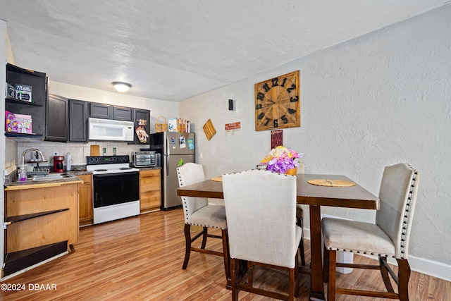 kitchen featuring white appliances, sink, light hardwood / wood-style flooring, and decorative backsplash