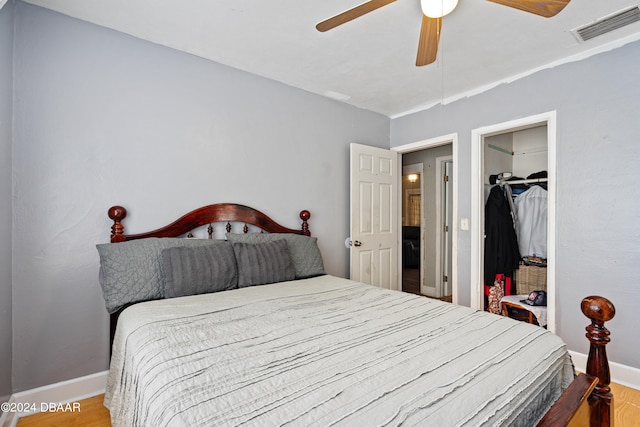 bedroom with ceiling fan, a closet, light wood-type flooring, and a walk in closet