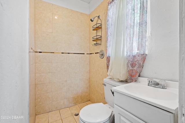 bathroom with toilet, vanity, tile patterned flooring, and a tile shower