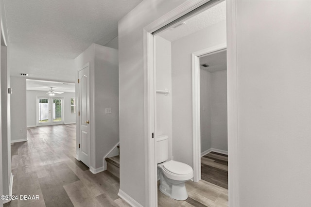 bathroom with french doors, wood-type flooring, a textured ceiling, and toilet