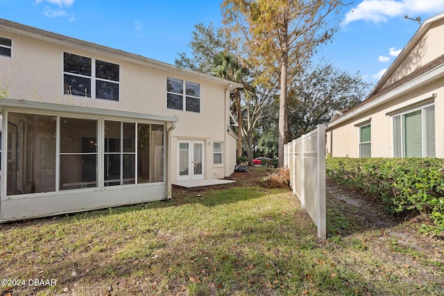 back of property with a lawn and french doors