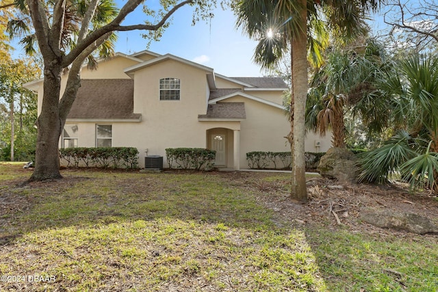 view of front of home with cooling unit and a front lawn