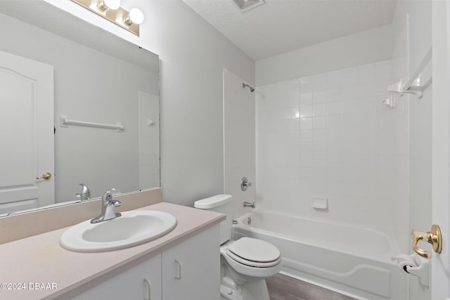 full bathroom featuring a textured ceiling, vanity, shower / washtub combination, hardwood / wood-style flooring, and toilet