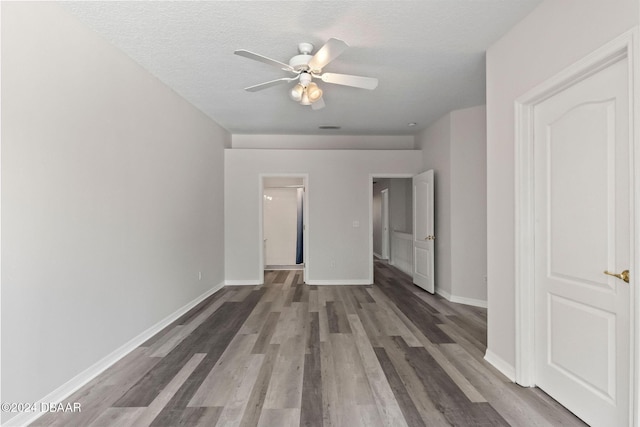 empty room with a textured ceiling, ceiling fan, and dark wood-type flooring