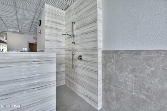 bathroom with tiled shower and tile walls